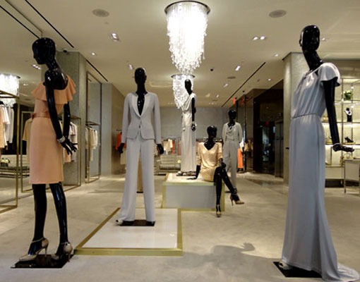 A woman is walking in front of a store window.