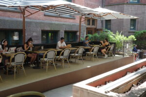 A group of people sitting at tables under an umbrella.