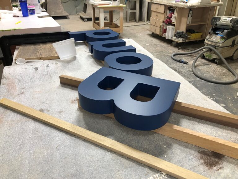 A blue sign sitting on top of a wooden board.